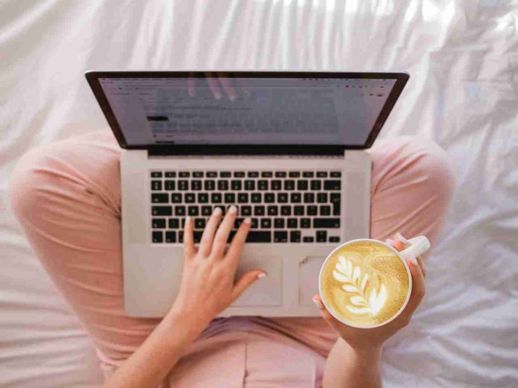 Una chica con un ordenador portatil creando su blog con un café